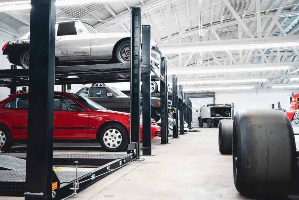 Automotive storage facility with multiple vehicles stacked on four-post car lifts.